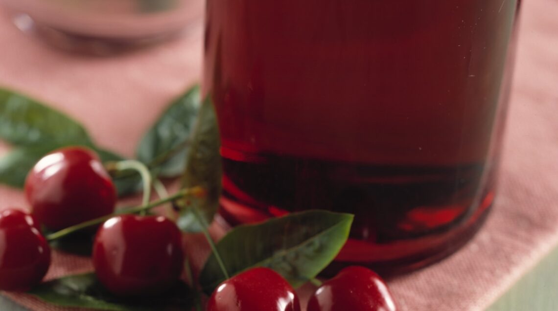 Bottiglia con liquido rosso e ciliegie