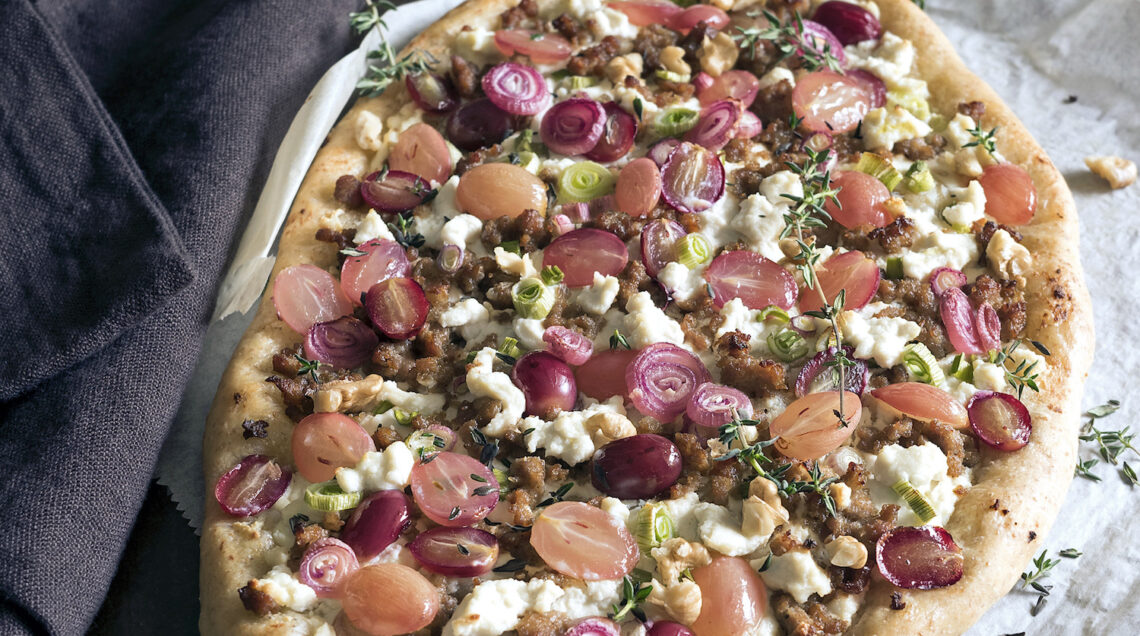 Pizza gourmet con ricotta, uva rosata e cipollotti rossi