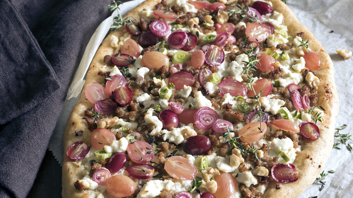 Pizza gourmet con ricotta, uva rosata e cipollotti rossi