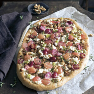 Pizza gourmet con ricotta, uva rosata e cipollotti rossi