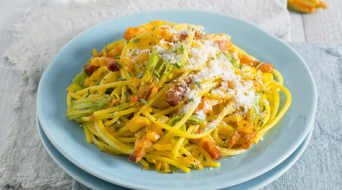 piatto di spaghetti con fiori di zucca, pancetta, grana e zafferano