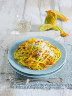 piatto di spaghetti con fiori di zucca, pancetta, grana e zafferano