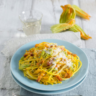 piatto di spaghetti con fiori di zucca, pancetta, grana e zafferano