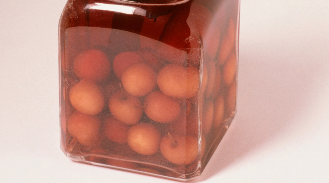 Dettaglio di una bottiglia di Cherry Brandy artigianale, con ciliegie intere immerse nel liquore