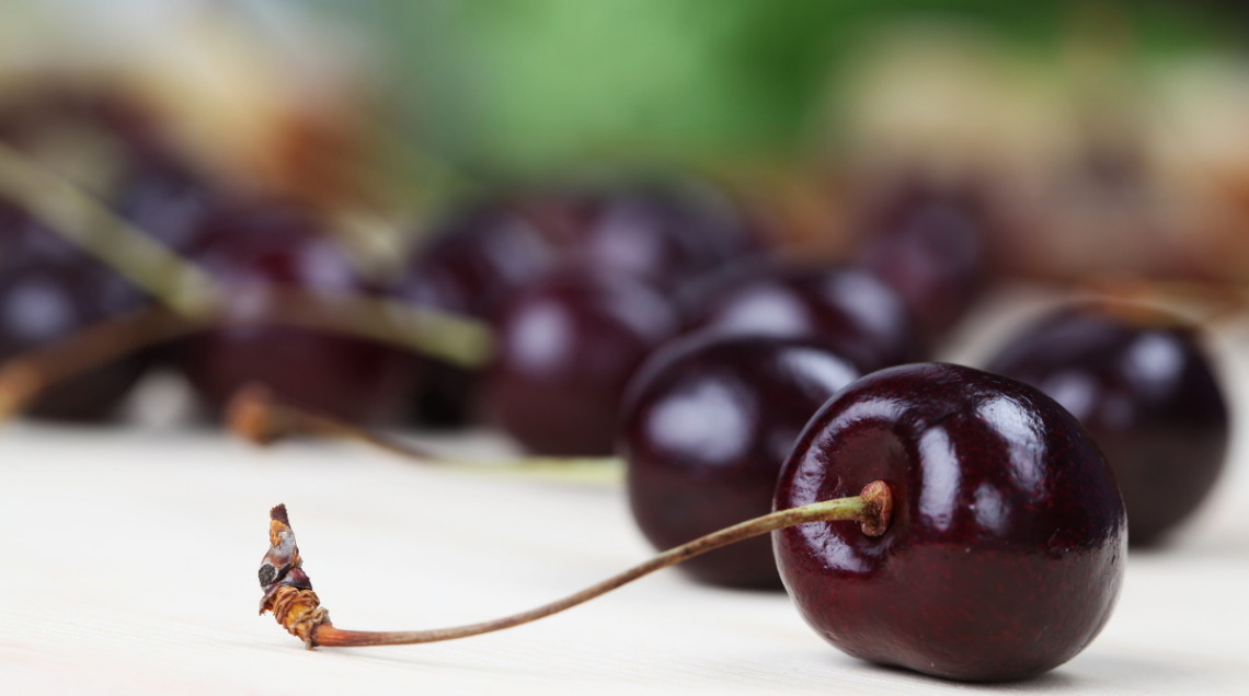 Frutti freschi di ciliegia nera con picciolo, in primo piano au un tavolo