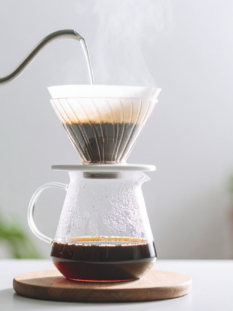 Estrazione di caffè filtro con metodo pour over manuale tramite bollitore a collo di cigno e caraffa di vetro.