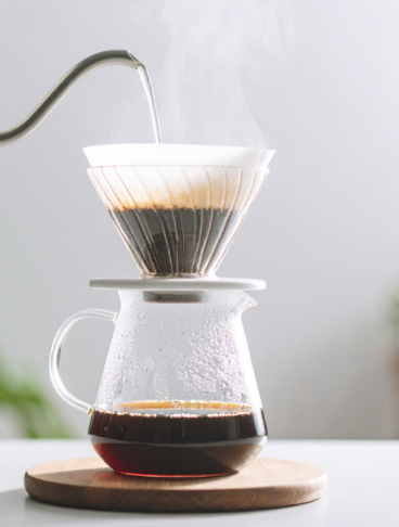 Estrazione di caffè filtro con metodo pour over manuale tramite bollitore a collo di cigno e caraffa di vetro.