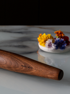 Immagine composita che mostra a sinistra il mattarello in legno Marcato Heritage con fiori colorati e a destra la macchina Atlas+ rossa che taglia gli spaghetti.