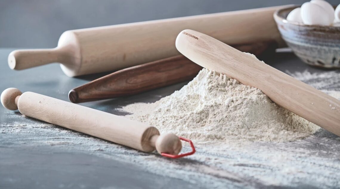 Matterello in legno e montagnetta di farina sulla spianatoria di marmo. intorno, altri tre matterelli di dimensioni diverse