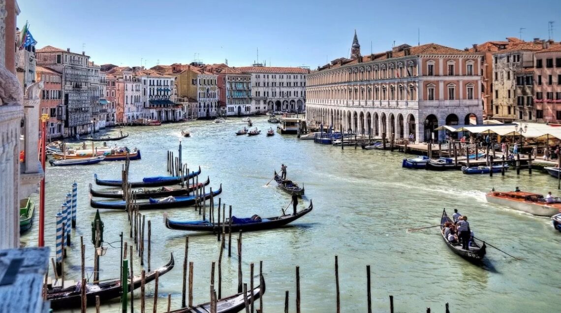 Veduta dai colori pastello del Canal Grande di Venezia, con splendidi Palazzi ai lati del canale e le tipiche gondole