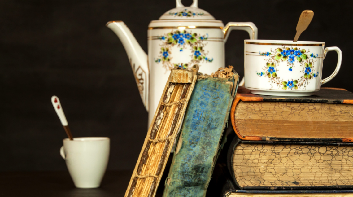 Caffettiera e tazzina d'epoca accanto a libri antichi, appoggiati sul tavolo