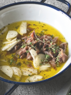 Filetti di acciughe o aringhe sott'olio con spicchi d'aglio e timo fresco in un piatto smaltato bianco e blu, simbolo dell'elogio del poco ma buono a tavola.