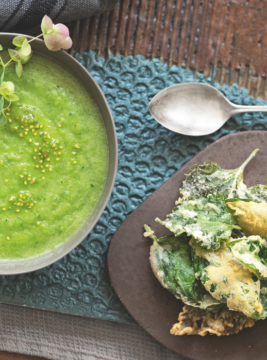 gazpacho verde dentro un piatto fondo e tempura di foglie di basilico e perilla su tagliere grigio