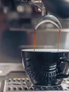 Il caffè: primo piano di una tazzina che viene riempita nella macchina del bar