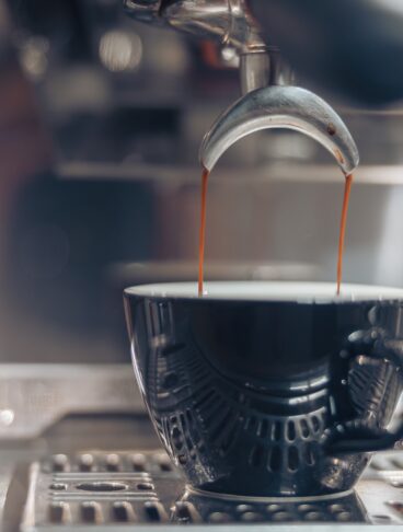 Il caffè: primo piano di una tazzina che viene riempita nella macchina del bar