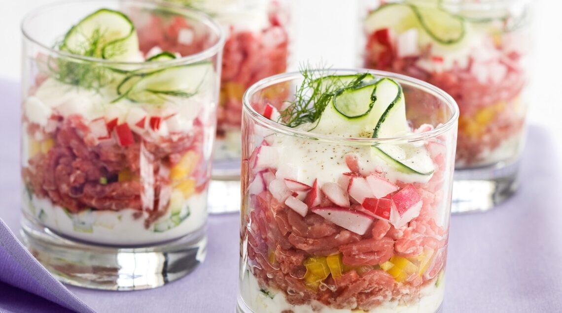 quattro bicchieri trasparenti con tartare di manzo e verdure croccanti per un ferragosto rinfrescante e goloso