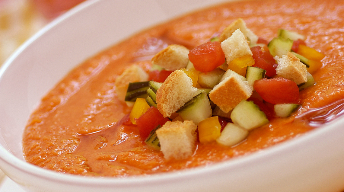 Gazpacho andaluso, la tipica zuppa fredda di pomodoro, guarnita in superficie con crostini di pane e verdure fresche a cubetti.