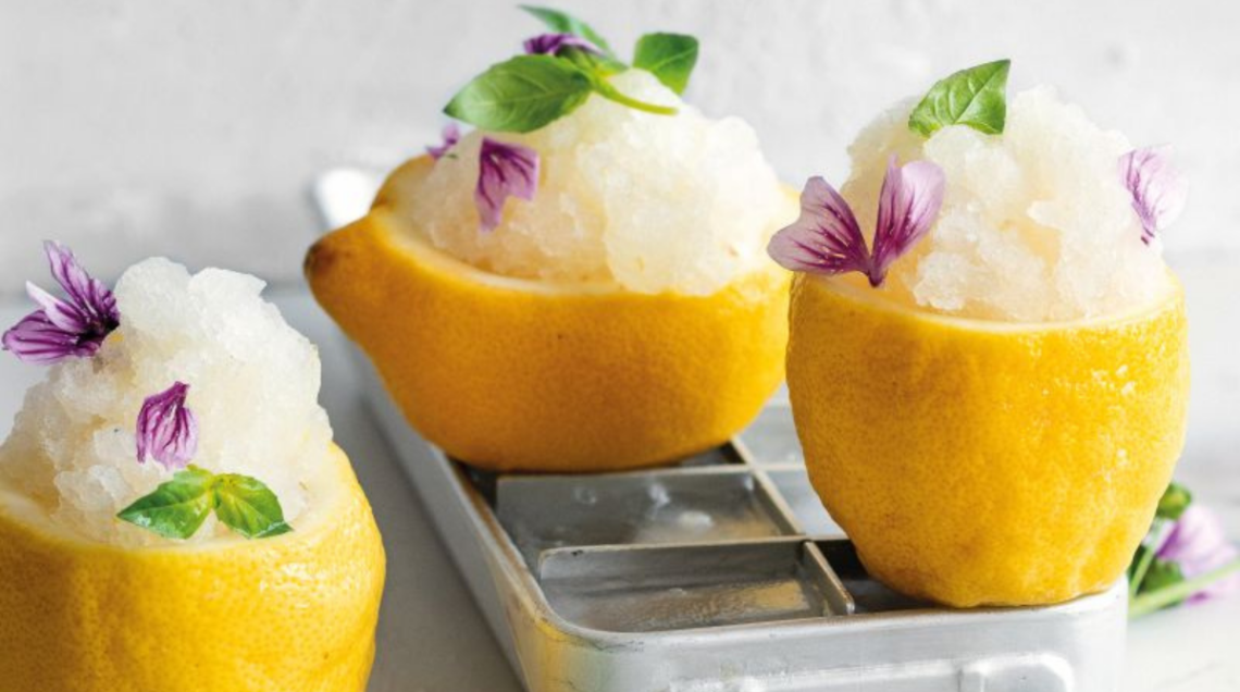3 limoni tagliati a metà e privati della loro polpo contengono una granita di limoni al bergamotto e basilico