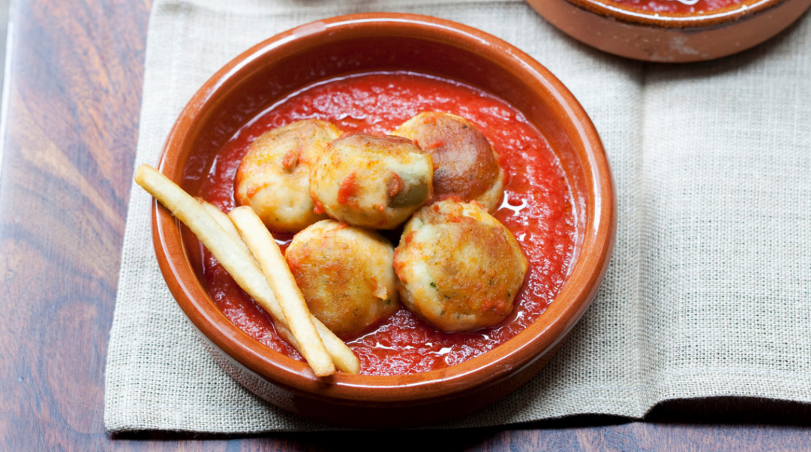 Ciotola di terracotta contenente il bacalao andaluso, quindi polpettine di baccala in salsa di pomodoro
