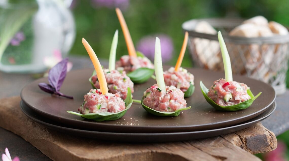 Finger food di polpettine di tartare alla senape con verdure su piatto nero
