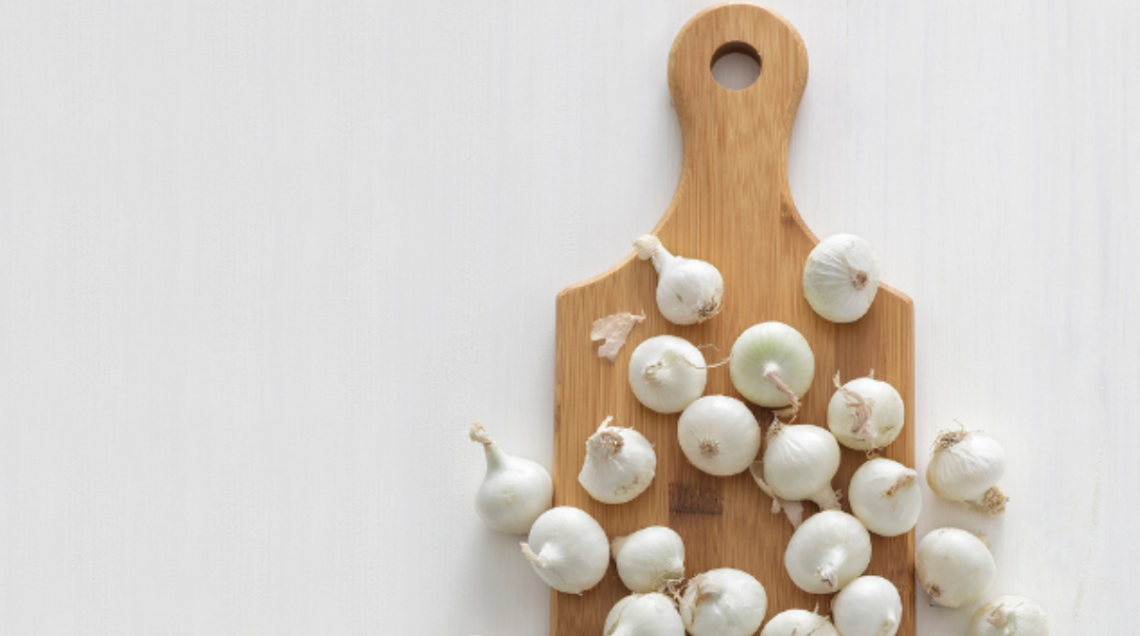 Cipolle bianche su tagliere di legno lungo