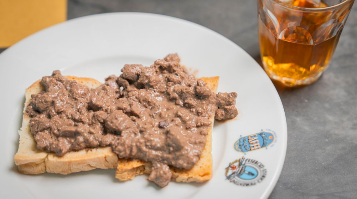 Crostino toscano su piatto bianco con affianco un bicchiere