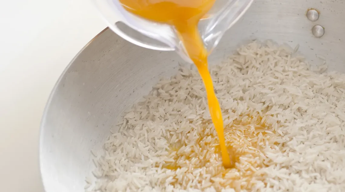 polvera di curcuma sciolta in acqua viene versata in un tegame colmo di basmati