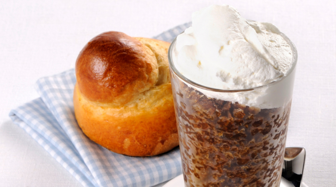 Granita al caffè con panna all'interno di un bicchiere di vetro e brioche con tuppo