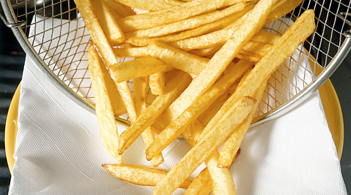 Patate fritte tagliate a fiammifero vengono versate su una carta fritti