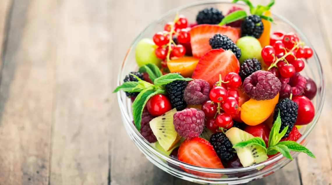 Una macedonia ricca di frutta come more, lamponi, pesche, ribes, fragole&c. in una ciotola di vetro