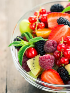 Una macedonia ricca di frutta come more, lamponi, pesche, ribes, fragole&c. in una ciotola di vetro