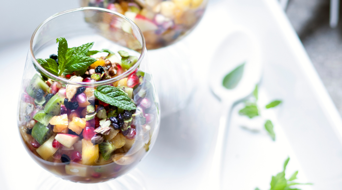 macedonia di frutta in bicchiere di vetro trasparente con erbe aromatiche
