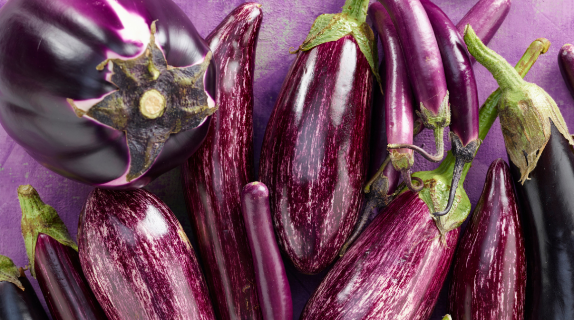 Diverse varietà di melanzane sono disposte in maniera casuale su sfondo viola