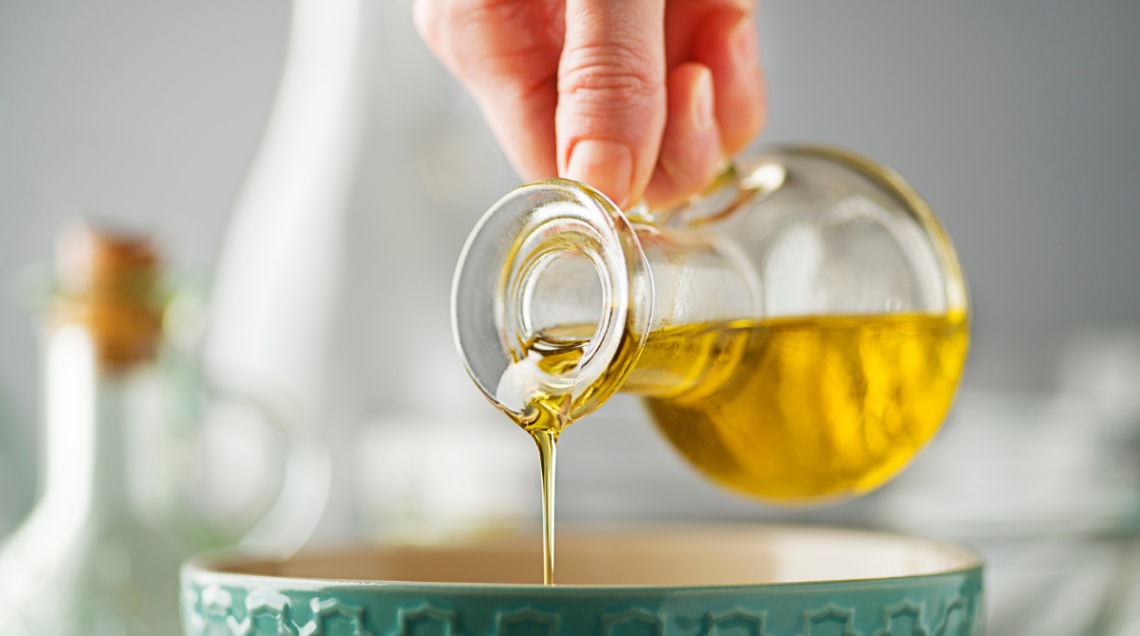 Una mano versa dell'olio in una ciotola verde