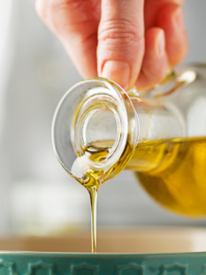 Una mano versa dell'olio in una ciotola verde
