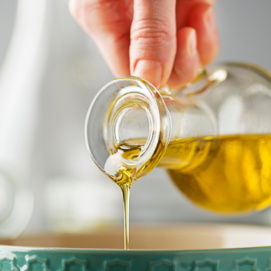 Una mano versa dell'olio in una ciotola verde
