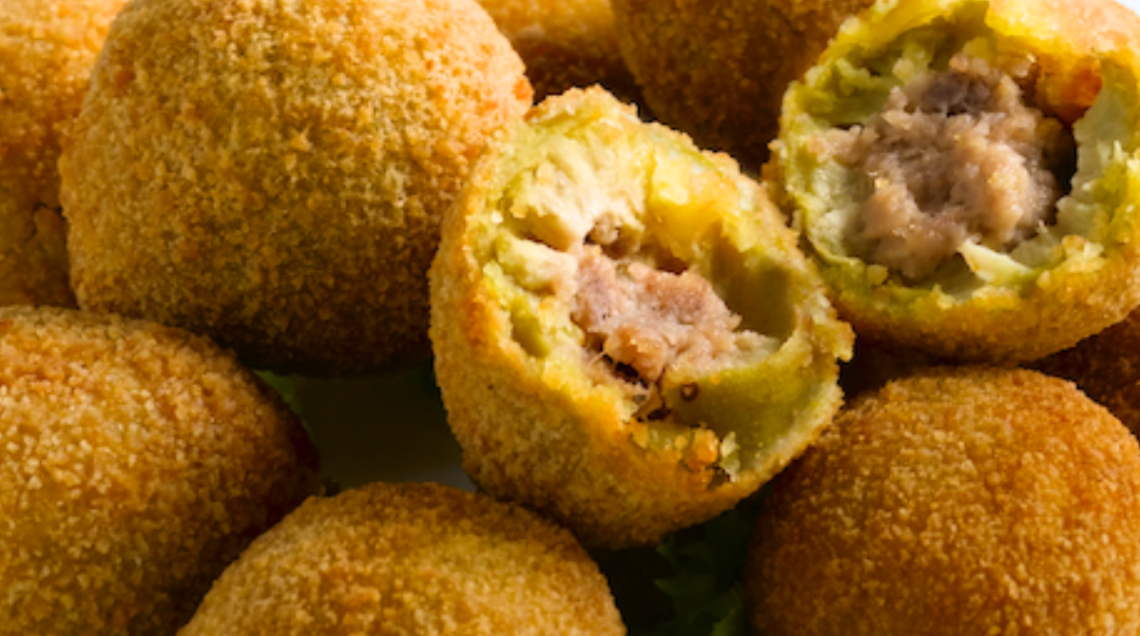 Olive ascolane fritte e dorate, alcune intere e altre tagliate a metà per mostrarne il ripieno.