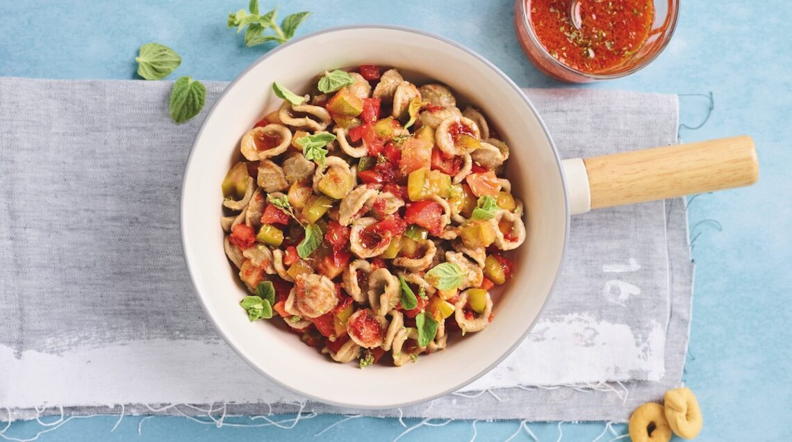 orecchiette al sugo crudo all'interno di una pentola chiara appoggiata su canovaccio