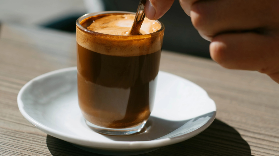 bicchiere di vetro trasparente su piattino bianco contenente un cortadito