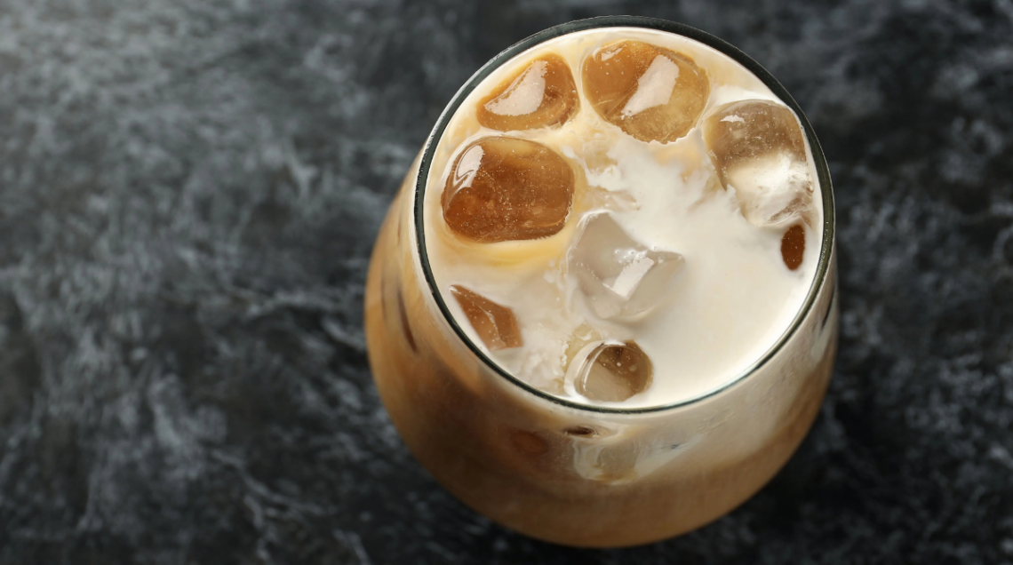 bicchiere trasparente colmo di caff&egrave; con viaggio