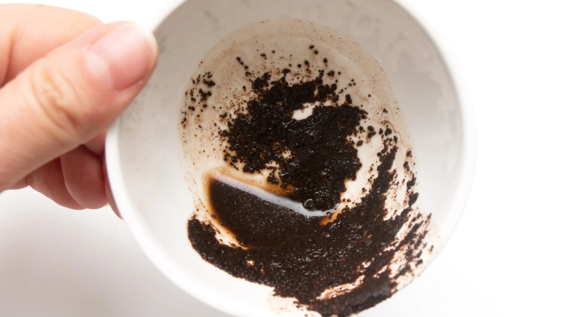 un fondo di caff&egrave; in un bicchierino bianco, tenuto in mano e visto dall'alto