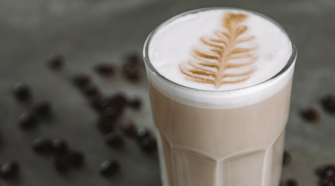 caff&egrave; latte all'interno di un bicchiere di vetro alto