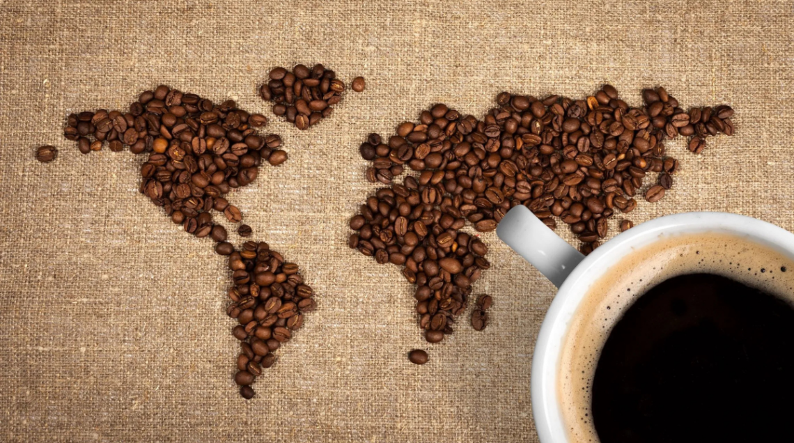 Una cartina, rappresentante diversi stati, fatta con chicchi di caffè. Affianco una tazza con del caffè