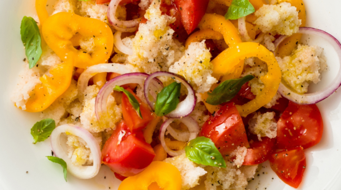 Panzanella estiva con peperoni gialli, pomodori, cipolle, pane ammorbito con aceto, foglie di basilico