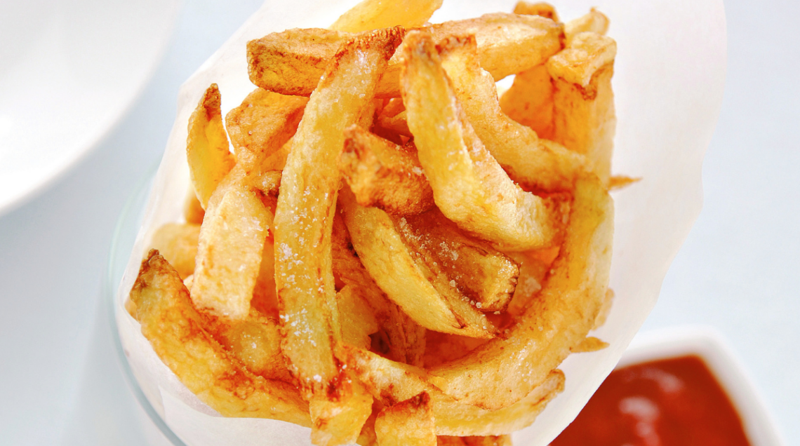 patatine fritte su sfondo bianco. Si intravede una salsa rossa in basso a destra