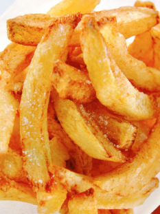 patatine fritte su sfondo bianco. Si intravede una salsa rossa in basso a destra