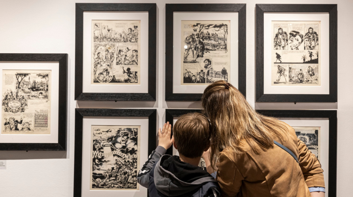 Una donna e un bambino guardano dei fumetti inquadrati in una delle sale del Palazzo del Fumetto