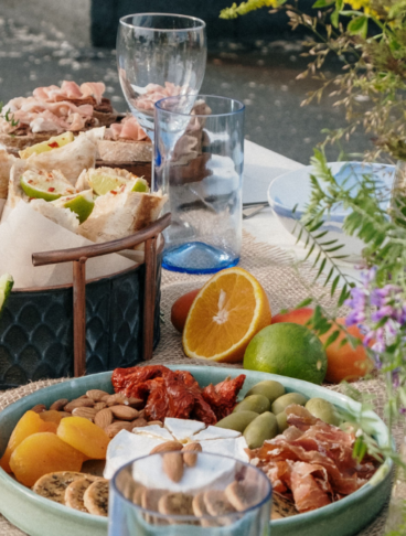 Tavola imbandita all'aperto con una varietà di antipasti e snack.
