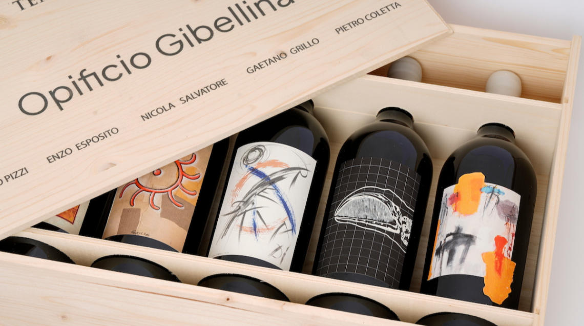 Cassetta di legno aperta contenente le bottiglie di vino dell'Opificio Gibellina con le etichette d'arte contemporanea di Tenute Orestiadi. 