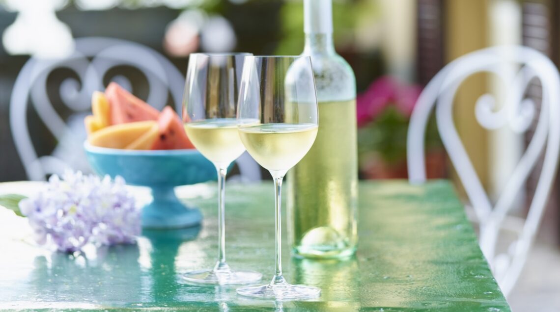 calici e bottiglia di vino al sole